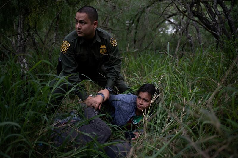 A border patrol agent apprehends a woman and a man after they were caught illegally crossing into the US border from Mexico near McAllen, Texas, on May 2, 2018. Reuters