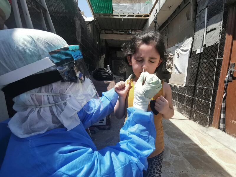 A member of a medical team that works with mobile coronavirus disease (COVID-19) testing units wears protective gear as he takes a swab from a child to track new cases of COVID-19, in Najaf, Iraq.  REUTERS