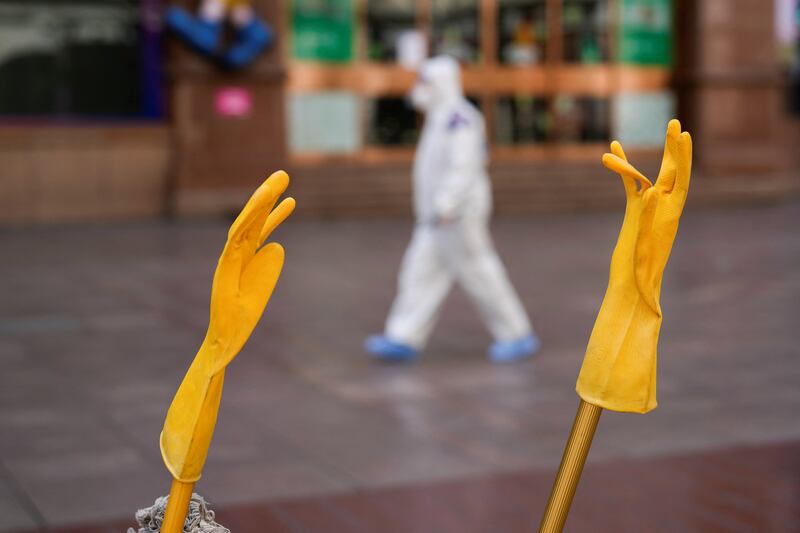 A pair of rubber gloves is hung to dry, as a security guard walks along a street in Shanghai. Reuters