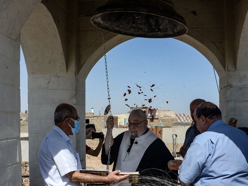 People gather as a priest rings the newly inaugurated bell at Syriac Christian church of Mar Tuma in Iraq's second city of Mosul, in the northern Nineveh province, on September 18, 2021.  - The church bell was inaugurated today to the cheers of Iraqi Christians,  seven years after the Islamic State group (IS) overran the city and proclaimed it their "capital", before they were driven out three years later by the Iraqi army after months of gruelling street fighting.  (Photo by Zaid AL-OBEIDI  /  AFP)