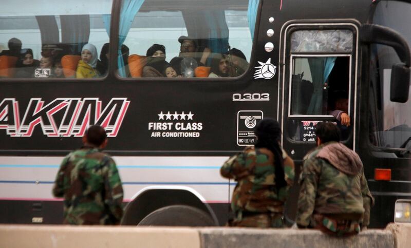 Syrian rebels and civilians look through a bus window as they leave Harasta in eastern Ghouta, in Damascus, Syria on March 23, 2018. Omar Sanadiki / Reuters