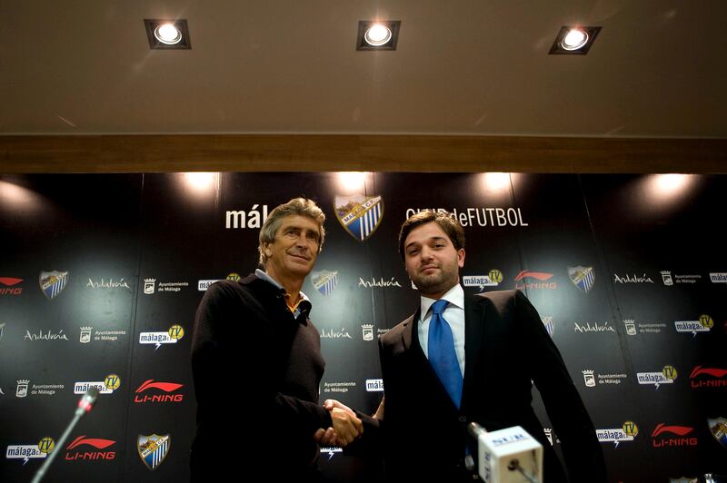 Malaga's Chilean new coach Manuel Pellegrini (L) shakes hands with Malaga's vice president Abdullah Ghubn prior to give a press conference during Pellegrini's official presentation at the Rosaleda stadium in Malaga, on November 5, 2010.   AFP PHOTO/ JORGE GUERRERO

