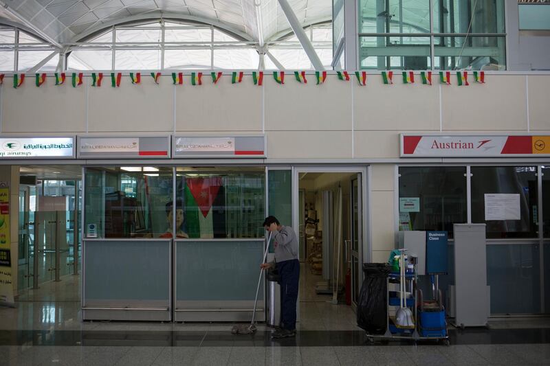 An airport employee cleans the floor in front of closed airline desks at the Irbil International Airport in Iraq, Saturday, Sept. 30, 2017. On Friday evening the Iraq federal government instituted a flight ban that halted all international flights from servicing the Kurdish region's airports. (AP Photo/Bram Janssen)