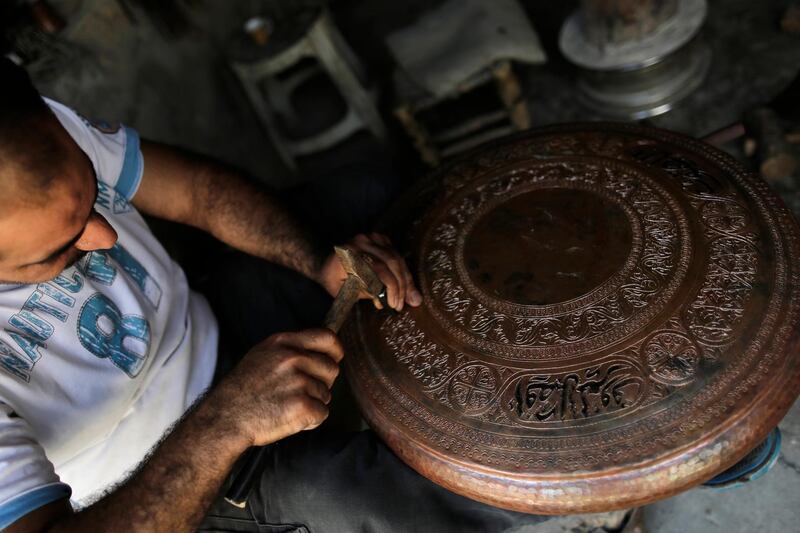 In this  photo, Ahmad Zuhdi Ghazoul works on a piece of copper on the newly renovated copper market in Aleppo, Syria. He has been a copper worker for three decades.AP