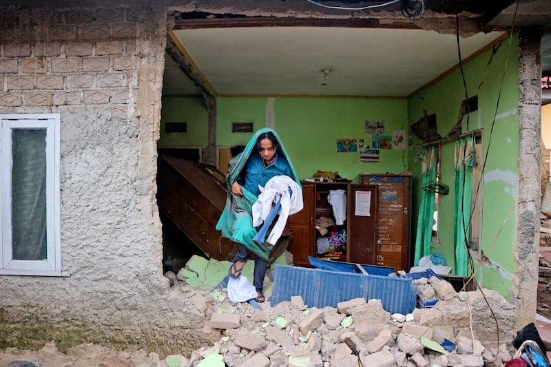 A man collects clothes from his damaged house in Cianjur. AP