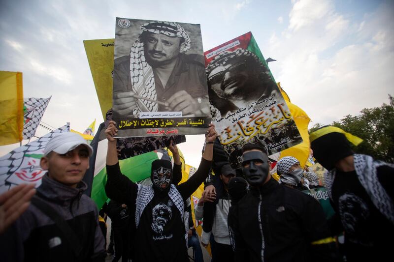 Palestinians hold portraits of Palestinian leader Yasser Arafat and wave yellow Fatah flags during a march to mark the 16th anniversary of his death, in the West Bank city of Ramallah. AP Photo