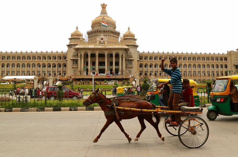 epa06753949 An Indian tongawalla takes a ride in front of the Vidhana Soudha, the seat of the State Legislature of Karnataka, Bangalore, India, 21 May 2018.  EPA/JAGADEESH NV