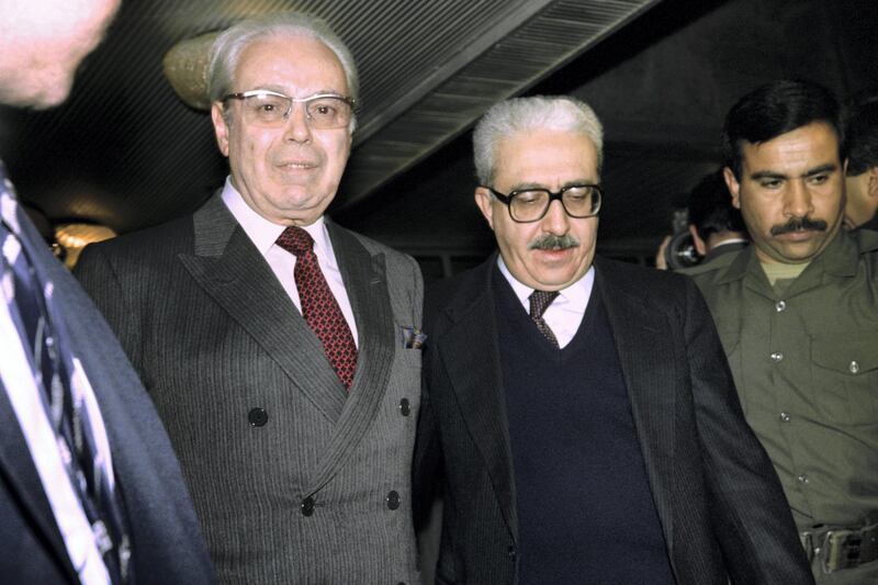 UN Secretary General Javier Perez de Cuellar (L) is accompanied by Iraqi Foreign Minister Tareq Aziz upon his arrival on Januray 12, 1991 to hold last chance peace talks with Iraqi President Saddam Hussein. (Photo by Gerard FOUET / AFP)