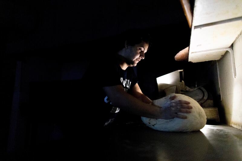 A pizza maker uses battery powered lamps to illuminate his work space during a blackout inside the delivery-only pizza shop in Buenos Aires, Argentina.  AP