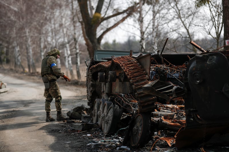 Ukrainian servicemen inspect the remains of a Russian tank. EPA