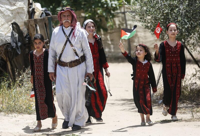 Palestinian refugee Mahmoud Abu Deeb, 82, a former fighter from the village of Beersheba, walks with family members outside his home in Khan Yunis in the southern Gaza Strip. AFP