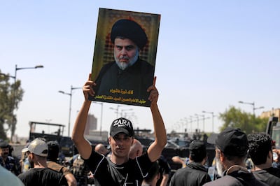 A supporter of Moqtada Sadr holds up the Shiite cleric's portrait as demonstrators gather in Tahrir Square in central Iraq. AFP