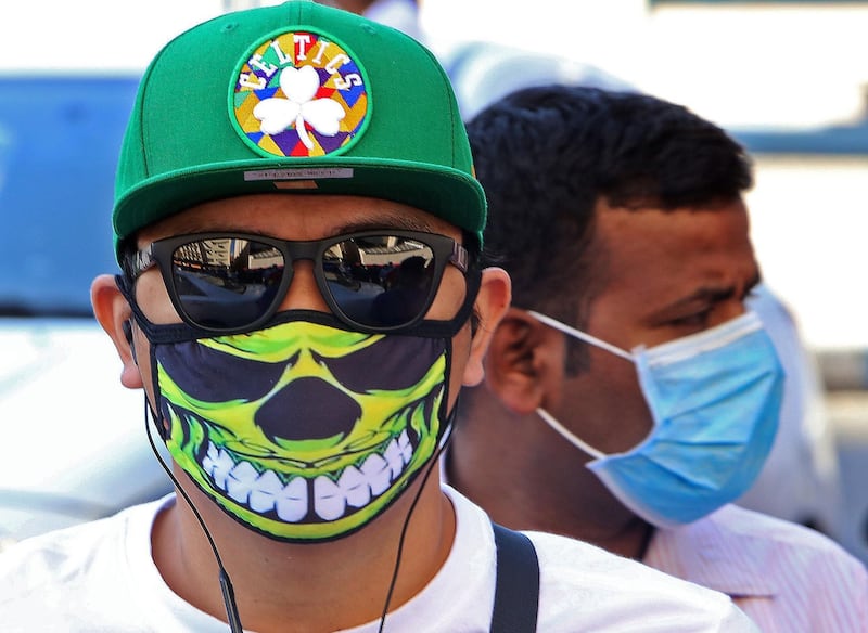 People wearing protective masks are seen on a street in Kuwait City, amid a global outbreak of the novel Coronavirus.  AFP