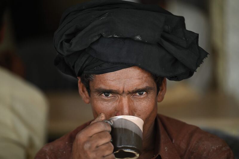 Men drink a cup of tea at a roadside restaurant in Islamabad on June 15, 2022.  - A Pakistani minister has caused a storm in a teacup by urging citizens to cut back on drinking "chai" as a way to preserve foreign currency that pays to import the leaves used in brewing the popular beverage.  (Photo by Aamir QURESHI  /  AFP)