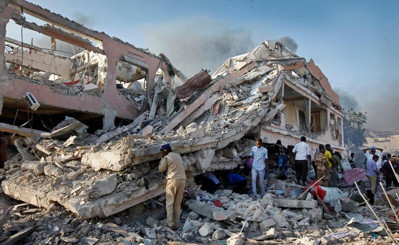 FILE - In this Saturday, Oct 14, 2017, file photo, people gather to search for survivors by destroyed buildings at the scene of a blast in the capital Mogadishu, Somalia. Somalia is marking the first anniversary of one of the world's deadliest attacks since 9/11, a truck bombing in the heart of Mogadishu that killed well over 500 people. The Oct. 14, 2017 attack was so devastating that the al-Shabab extremist group that often targets the capital never claimed responsibility amid the local outrage. As Somalis gather at a new memorial with a minute of silence, local media report that the man accused of orchestrating the bombing has been executed. (AP Photo/Farah Abdi Warsameh-File)