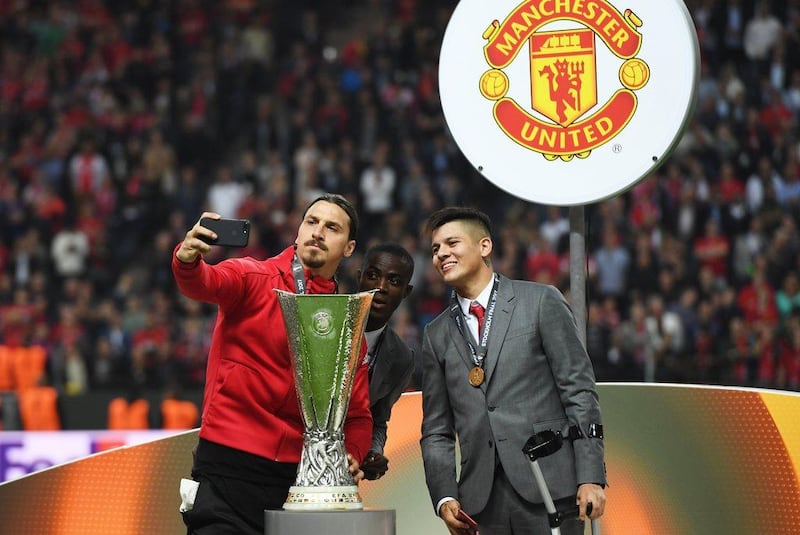 Injured Manchester United players Zlatan Ibrahimovic, left, Eric Bailly, centre, and Marcos Rojo take a selfie with the Europa League. Georgi Licovski / EPA