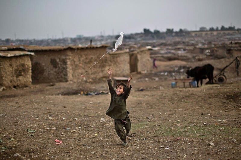 An Afghan refugee child chases a kite launched by his sister while playing in a field near their home on the outskirts of Islamabad, Pakistan. Muhammed Muheisen / AP Photo