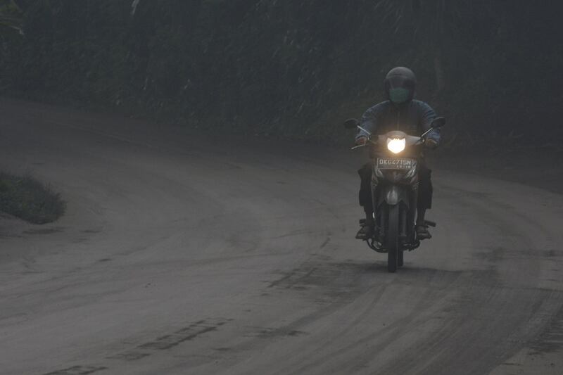 A motorist rides his motorbike during a shower of ash and rain from Mount Agung volcano during an eruption in Bebandem Village, Karangasem, Bali, Indonesia. Antara Foto / Fikri Yusuf / via Reuters