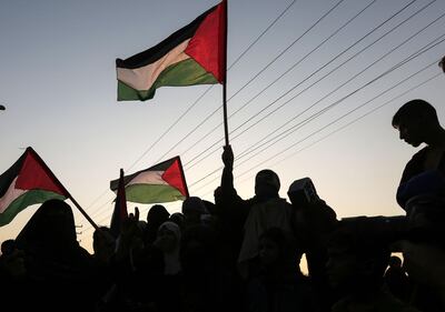 TOPSHOT - Palestinian protesters wave their national flags at sunset during a demonstration near the Erez crossing with Israel on September 4, 2018, in the northern Gaza Strip protesting against the United States decision to stop funding and backing the United Nations agency for Palestinian refugees(UNRWA). (Photo by MAHMUD HAMS / AFP)