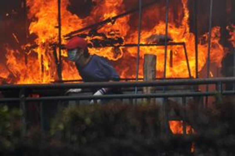 A Thai Red Shirt anti-government protester runs beside a shop set ablaze a few hours before the leaders of the movement announced their surrender inside the protesters' camp in downtown Bangkok on May 19, 2010.
