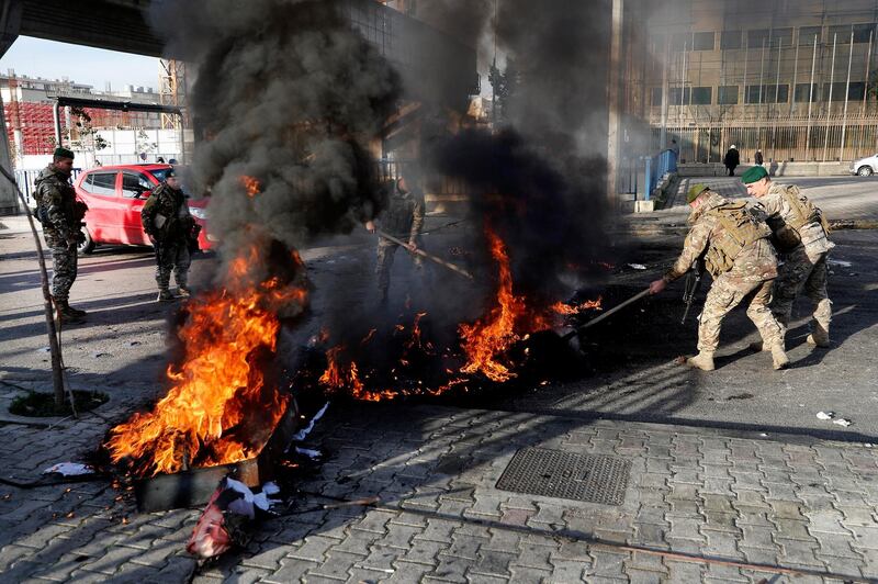 Lebanese soldiers try to remove burning tires set on fire by the anti-government protesters to block the southern entrance of a highway during a protest against the newly formed cabinet. AP