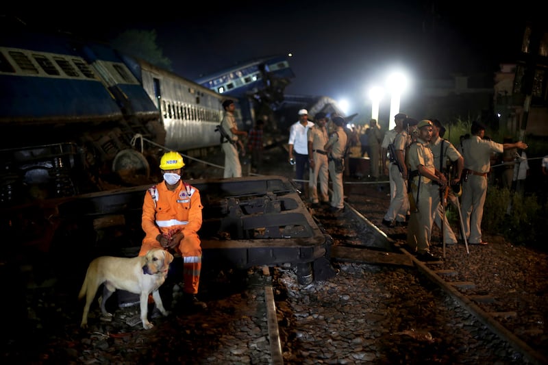 A man from National Disaster Response Force (NDRF) takes a break from rescue operations next to the upturned coaches of the Kalinga-Utkal Express. Altaf Qadri / The Associated Press
