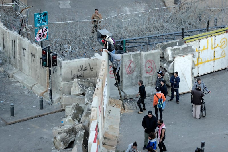 Anti-government protesters climb a concrete wall installed by authorities to keep protesters far from the main Lebanese government headquarters and open road to parliament, in downtown Beirut, Lebanon. AP Photo
