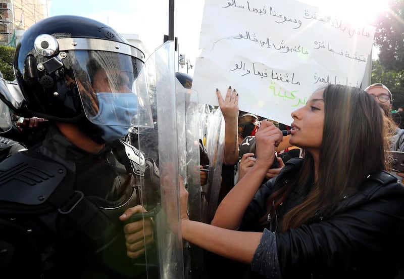 A Tunisian anti-government protester puts lipstick in front of anti-riot policemen during a demonstration in Tunis, Tunisia. EPA