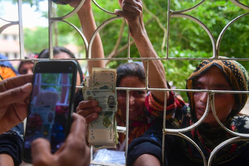 Displaced women show their national identity cards at a government office in Sukkur as they wait to receive 25,000 Pakistani rupees ($112) in compensation for their damaged houses. AFP