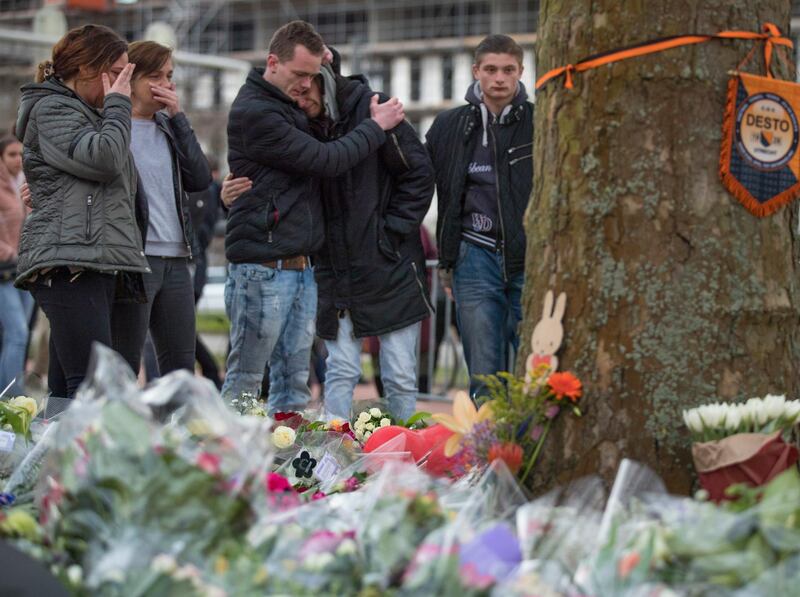 People cry after laying flowers at a makeshift memorial site for the victims of a shooting incident in a tram in Utrecht, Netherlands, Tuesday, March 19, 2019. A gunman killed three people and wounded others on a tram in the central Dutch city of Utrecht Monday March 18, 2019. (AP Photo/Peter Dejong)