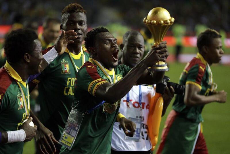 Cameroon players run celebrating with the trophy. Sunday Alamba / AP Photo