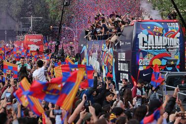 The players and staff of FC Barcelona men football team parade aboard a open-top bus followed by the women's team (out of frame), to celebrate their La Liga titles in Barcelona on May 15, 2023.  The FC Barcelona women's team won its fourth consecutive La Liga title on April 30 after scoring 3-0 against Sporting de Huelva at the Estadi Johan Cruyff while the men's team yesterday won their 27th La Liga tile by thrashing Espanyol 4-2, wrestling the title back from rivals Real Madrid.  (Photo by Lluis GENE  /  AFP)