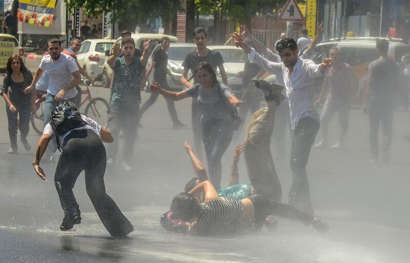 Demonstrators are hit by a water cannon as they clash with riot police during a protest against the replacement of Kurdish mayors with state officials in three cities, in Diyarbakir.  AFP