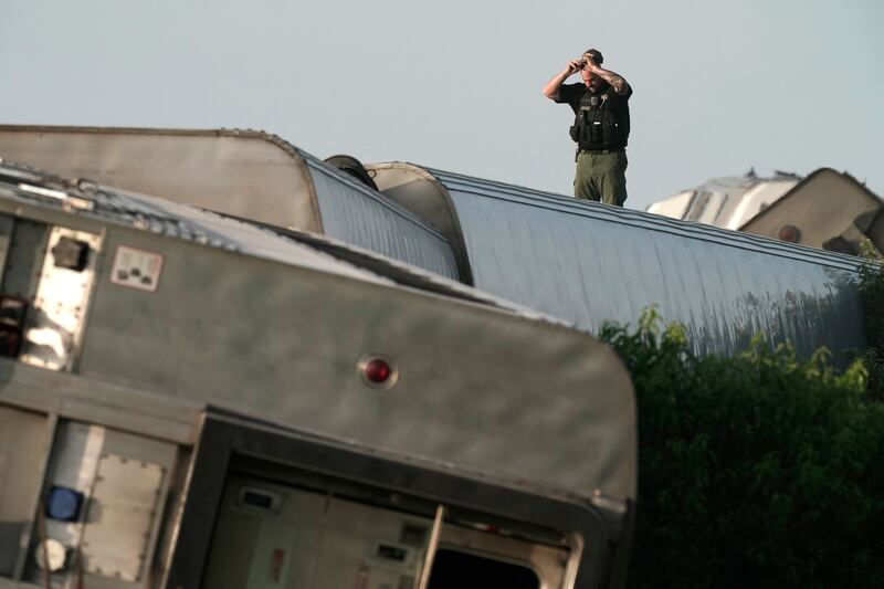 A law enforcement officer inspects the scene of an Amtrak train which derailed after striking a dump truck Monday, June 27, 2022, near Mendon, Mo.  (AP Photo / Charlie Riedel)