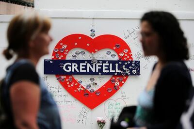 Messages of condolence for the victims of the Grenfell Tower fire are pictured on a fence near to the burned-out shell of Grenfell Tower block in west London on June 13, 2018. Commemorations begin on June 13, 2018, to honour the 71 people who died when a fire ripped through the Grenfell tower block in London one year ago. / AFP / Daniel LEAL-OLIVAS
