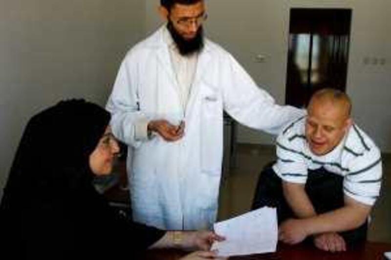 (From left to right) Sonia AlHashimi, President of the UAE Down Syndrome Association, Hani Al-Amayreh, Occupational Therapy Specialist and Saif Aldabal look at some of Saif's finished writing exercises, at the UAE Down Syndrome Association, in Dubai, UAE, on April 15, 2010. (Ana Bianca Marin For The National).