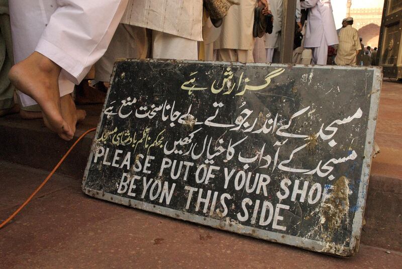 Please take of yout shoes signs adorns the entrance to Lahore famous Mughal inspired Badshahi Mosque, Lahore, Pakistan by Matthew Tabaccos for The National.21.12.08