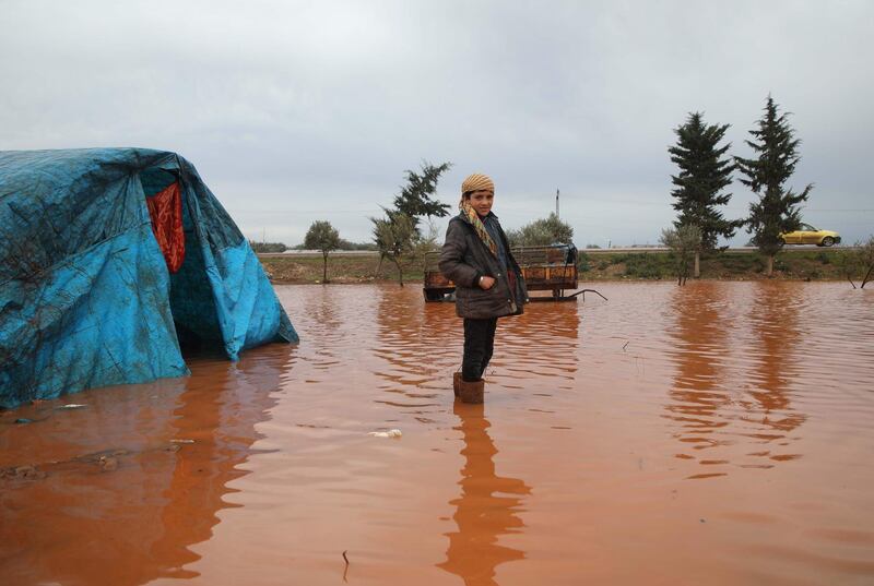 A Syrian boy, stands in a water logged field outside a tent in the Cordoba camp for internally displaced Persons (IDP), close to Batabu town, along the highway leading to the Syrian Bab al-Hawa border crossing with Turkey, in the northern Syrian Idlib province. Following heavy rain storms, the camp has become water logged, flooding the tents and making the the roads muddy and difficult to maneuvre on.  AFP