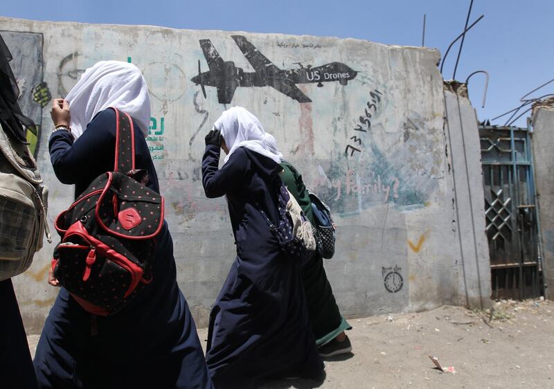 Yemeni female students walk past graffiti protesting US drone airstrikes.  EPA