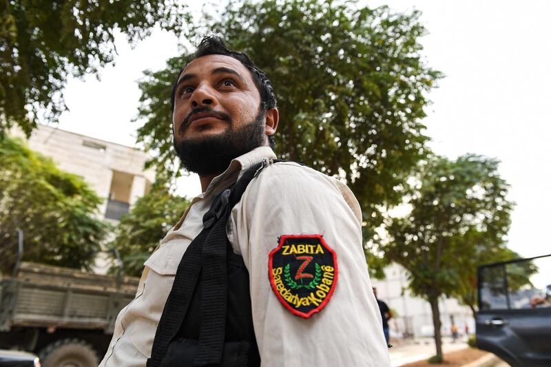 A member of the local Syrian Kurdish police in the town of Kobane along the border with Turkey in the north of Aleppo governorate, looks on as Syrian government forces deploy there.  AFP