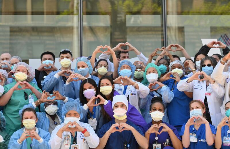 Nurses and healthcare workers gesture hearts in celebration of Nurse Week and International Nurses Day outside Mt. Sinai Oueens in the Queens borough of New York City on May 12, 2020. (Photo by Angela Weiss / AFP)