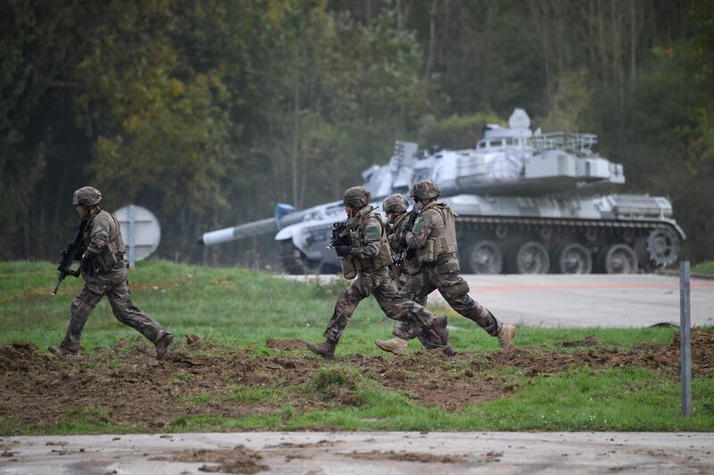 Soldiers run past an AMX-30 battle tank during a presentation drill to the French Institute of Advanced Studies in National Defence (Institut des hautes Etudes de Defense Nationale) of the means of the French army ground force on October 19, 2017 in Versailles-Satory. / AFP PHOTO / Eric FEFERBERG