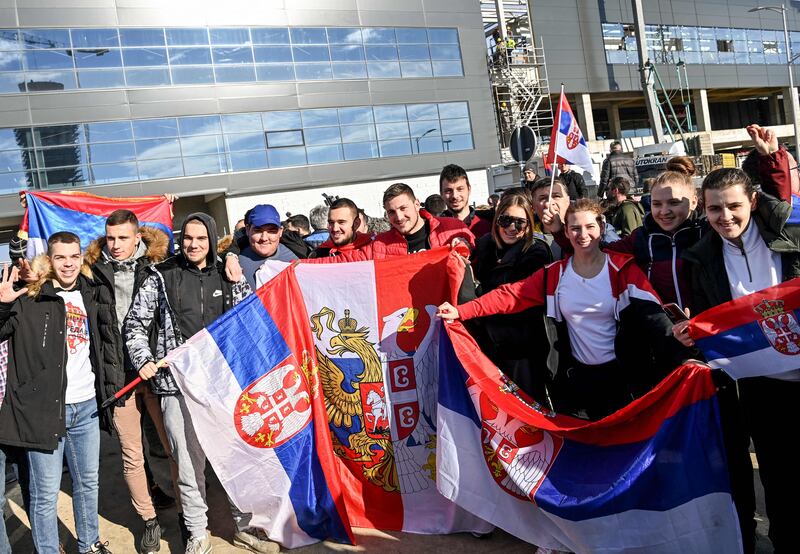 People holds Serbian national flags while waiting outside the VIP exit of Belgrade's international airport. AFP