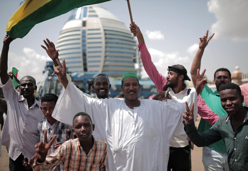 Sudanese men celebrate outside the Friendship Hall in the capital Khartoum where generals and protest leaders signed a historic transitional constitution meant to pave the way for civilian rule in Sudan.  AFP