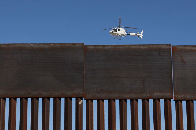 A US Customs and Border Protection helicopter flies over the border wall during a safety drill in the Anapra area in Sunland Park, New Mexico, United States, across from Ciudad Juarez, Chihuahua state, Mexico, on January 31, 2019. / AFP / Herika Martinez
