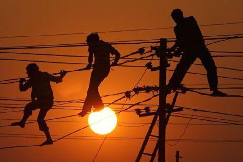 Linemen repair high tension wires on the banks of the Ganges River in Allahabad. Many Indians in rural areas have no access to electricity. Rajesh Kumar Singh / AP Photo