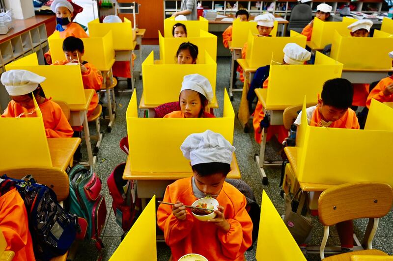 Pupils eat their lunch on desks with plastic partitions in Taipei, Taiwan. The country shut down the island nation of 23 million before cases could spread from mainland China. But it has failed to secure a deal to buy any of the advanced vaccines. Sam Yeh / AFP
