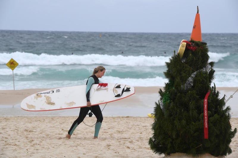 A surfer walks past a Christmas tree at Bondi Beach on Christmas Day in Sydney, Australia on December 25, 2017. Dean Lewins / AP