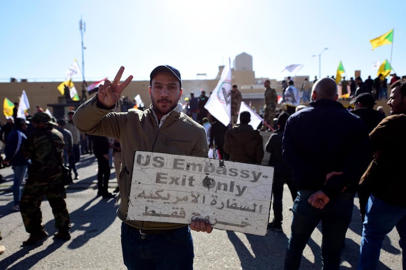 A man holds a sign taken from the US embassy premises during a protest in Baghdad.  EPA