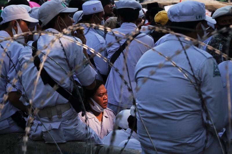 Security guards from a Muslim organisation stand by barbed wire separating them from police guarding the area around the presidential palace during a demonstration in Jakarta, Indonesia. Getty Images